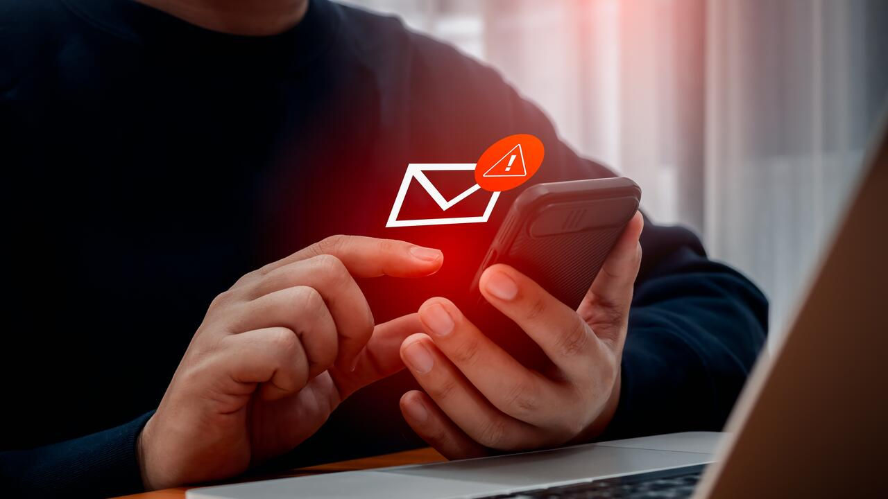 SMS spam, fake text message phishing from scammer concept. System hacked red warning alert, email hack, scam malware spreading virus on message alert virtual on mobile phone screen in person hand.